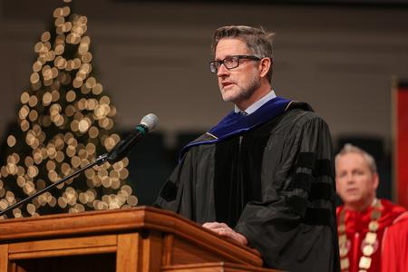 Michael Schiebout, associate professor of biology, gives the scripture reading at the beginning of fall graduation. - Photo by Kristi McMurry Woody