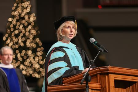 Renee Dauer, associate professor and chair of organizational leadership, reads scripture at the beginning of the second fall graduation service.  - Photo by Kristi McMurry Woody