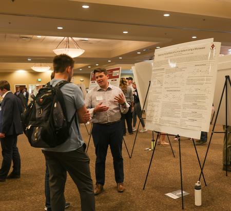 Evan Holt, senior chemistry major, shares his poster presentation entitled "Greening the Synthesis of a Chiral Sorbent Using a Microwave" during the Scholarship Symposium. - Photo by Suzanne Rhodes