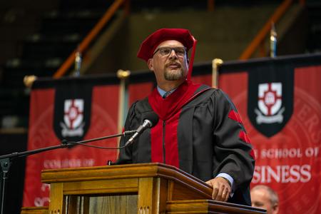 Kyle McClellan, senior pastor of Grace Church in Fremont, Nebraska, delivers the opening prayer at spring graduation. Kyle is the father of graduate Danielle McClellan. - Photo by Kristi McMurry Woody