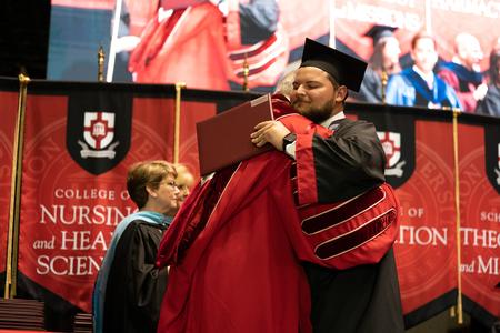 Grant Gammon, business graduate, receives his diploma and a hug from President Dub Oliver during spring graduation. - Photo by Kristi McMurry Woody