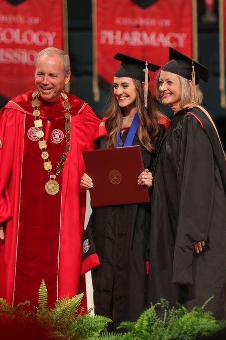 Sarah Emery, MBA graduate, receives her diploma with President Dub Oliver, and her mom, Brooke Emery, associate dean for the McAfee School of Business. - Photo by Suzanne Rhodes