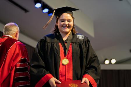 Hattie Thomasson smiles as she receives her accounting degree during the fall undergraduate commencement ceremony. - Photo by Kristi McMurry Woody