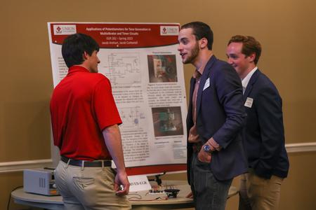Engineering majors Jacob Carbonell and Jacob Arehart describe their poster presentation entitled "Creating A Tunable Astable Multivibrator" to Georg Pingen, professor of engineering, at the 2023 UUSS. - Photo by Eli Creasy