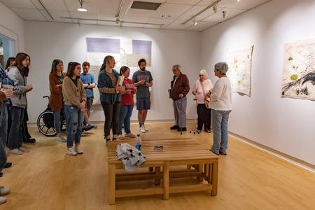 Paula Kovarik, full-time artist and fiber art workshop teacher from Memphis, Tenn., spoke with students who attended her recent exhibit in the art gallery that featured her stitching art. - Photo by Lyla Dietz