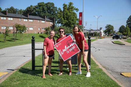 Life Group Leaders Sophie Dawson, Graham Abell, and Summer Smith waive welcome signs as new students drive onto campus for Move-In Day. - Photo by Karley Hathcock