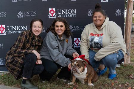 Brianna Pittman, Mylie Sparks, and Jalin Randolph pose with Buster at his retirement party during Homecoming week. - Photo by Lauren Steed