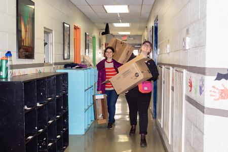 SAC Members Dona Kaci and Joelle Cruver carry boxes of furniture to assemble for the Boys & Girls Club in Humboldt on Campus and Community Day. - Photo by Lyla Dietz