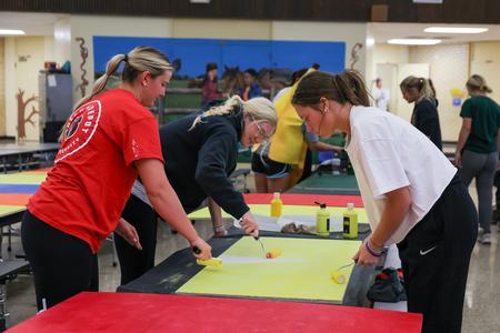 Members of the Softball team paint ceiling tiles for the cafeteria at Nova Early Learning Center during Campus and Community Day. - Photo by Karley Hathcock