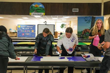 Members of the Softball team paint ceiling tiles for the cafeteria at Nova Early Learning Center during Campus and Community Day. - Photo by Karley Hathcock