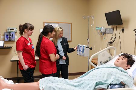 Shayla Alexander, assistant professor of nursing, teaches students how to use an IV infusion pump during a simulation lab. - Photo by Karley Hathcock