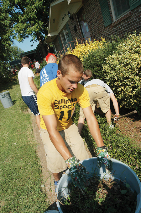 Michael Pugh, a sophomore soccer player at Union, helps remove weeds around a Jackson house Friday, Aug. 19. - Photo by Morris Abernathy