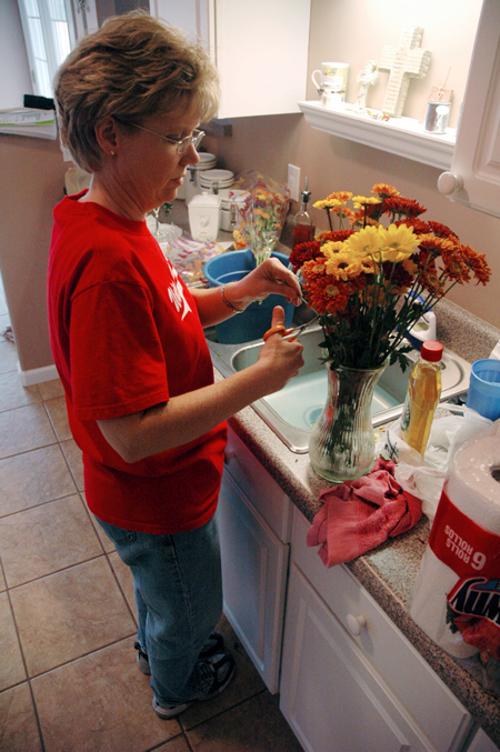 Cheryl Mercker of Health Services tends to a vase of flowers while cleaning and organizing the house of a mother and her three children during the Day of Remembrance. - Photo by Brad Moore