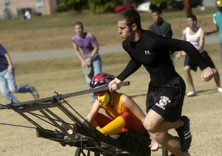 Freshman SAE Brian Bodnarchuk pulls Freshman Chi Omega Claire Yates during the chariott races at the Greek Olympics. - Photo by Kathleen Murray