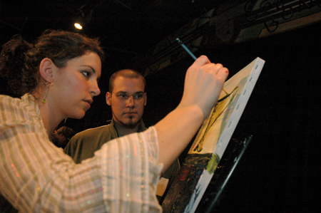 Senior Laura Berkemeyer paints during an interlude while alum Mark Westmoreland looks on at Cafe Bongo. - Photo by Brad Moore