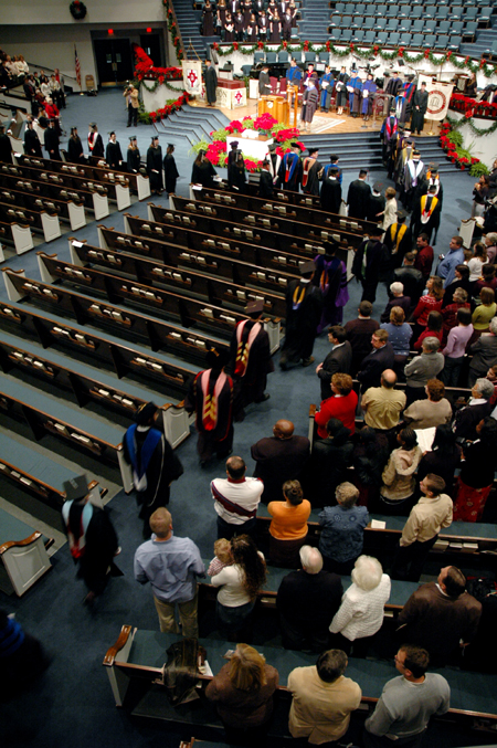 Graduates march in while their friends and families look on at the start of the fall graduation ceremony. - Photo by Brad Moore