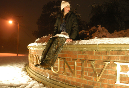Freshman Emily Blackketter takes a rest on the Union sign after playing in the snow. - Photo by Heather Phillips