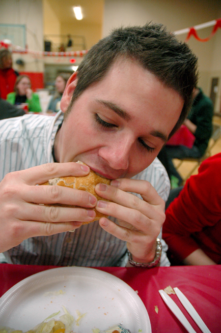 Junior Josh Wilkerson takes a bite from his hamburger during the World's Largest Tailgate Party. - Photo by Brad Moore