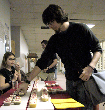 Ben Bailey picks up a cupcake containing multiple digits of pi on Pi Day 2006. - Photo by Stephanny Rodriguez