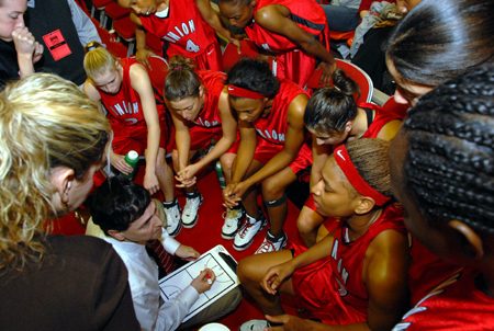 Head Coach Mark Campbell maps out a plan for victory in a sideline huddle during the NAIA Women's Basketball National Championship Game.  - Photo by Morris Abernathy
