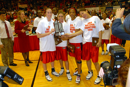 Seniors Peggy McCain, Jennifer Henson, Ena Daniels and Tiffany Fisher pose for pictures with a second consecutive NAIA national championship trophy. - Photo by Morris Abernathy