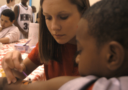 Allison (Smith) Yates paints the arm of a young boy at the Jackson Boys & Girls Club during The Spring Fling. The Spring Fling was an activity where the Club and SASW collaborated to make a day of excitement for at-risk kids while giving student social workers experience. - Photo by Heather Phillips