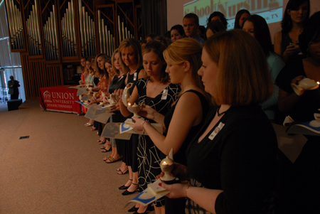BSN graduates pass the light from lamp to lamp during the lamplighting ceremony. - Photo by Morris Abernathy