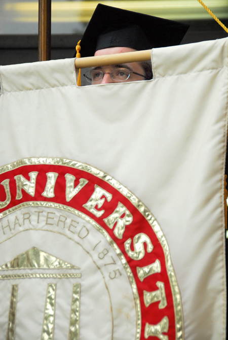 SGA President Landon Preston peeks through the university banner before the spring graduation processional to the Great Lawn. - Photo by Kyle Kurlick