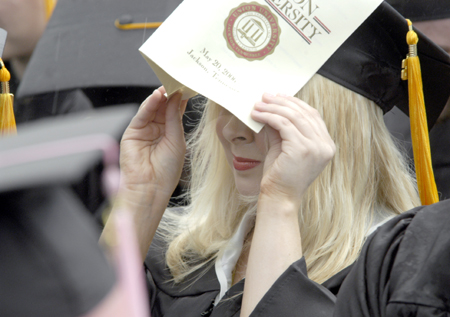A sudden rainstorm drove away many spectators during the latter stages of the graduation ceremony on the Great Lawn, but all 400 graduates remained in the rain until everyone received a degree. - Photo by Kyle Kurlick