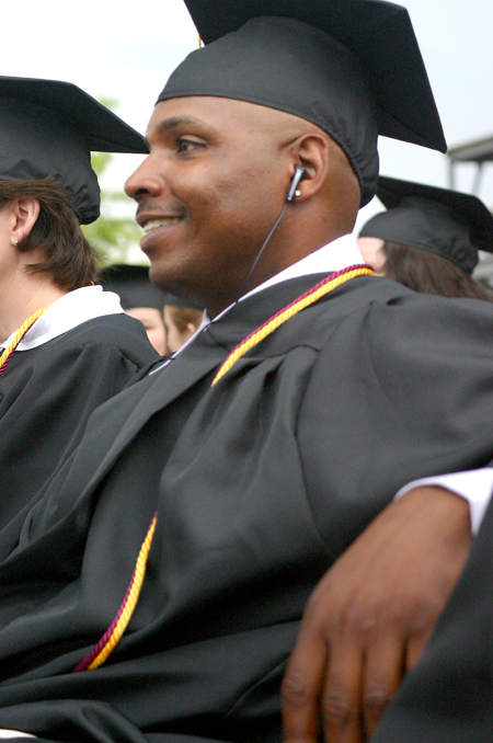 BSOL graduate Marcus Love entertains himself during the spring graduation ceremony before the rain begins to fall. - Photo by Stephanie Schroeder