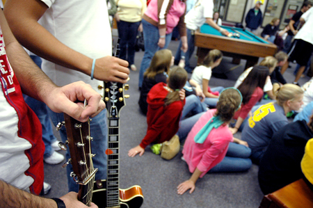 Roommates stand at the back of the crowd with their guitars during a New Student Orientation open mic event in the student lounge. - Photo by Kristen Nicole Sayres