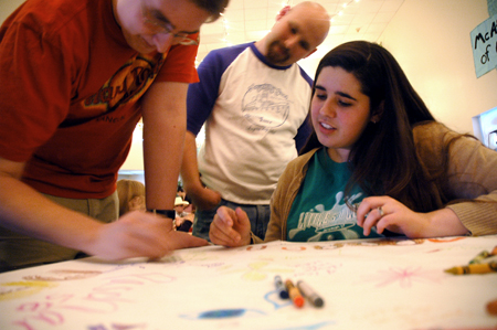 Sophomore Tyler Whetstone draws on the table cloth, while Juniors Ben Lancaster and Emily Orten watch during Mochafee, McAfee's annual coffee house. - Photo by Kristen Nicole Sayres