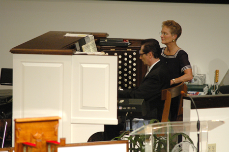 Ron Boud, professor of music, is assisted by his wife Jan while playing the processional during summer graduation. - Photo by Jim Veneman