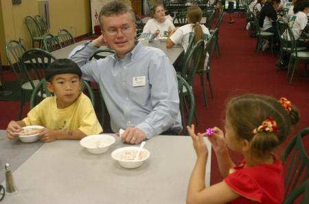 Director of Enrollment Services Robbie Graves sits with his children as they enjoy the ice cream served in Coburn during New Student Orientation. - Photo by Stephanie Schroeder