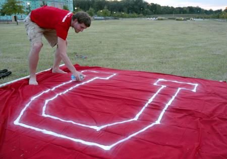 Ronald Long decorates paints the U on a flag for the pep rally march. - Photo by Kyle Kurlick