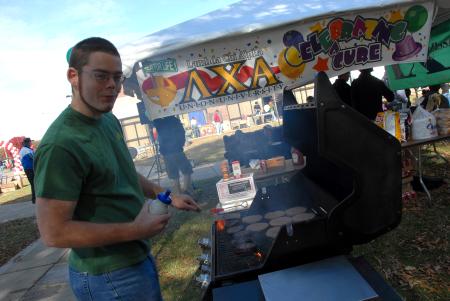 Senior Brody Ferrell cooks up some hamburgers for the LXA booth at the Arts in the Park event during Homecoming. - Photo by Morris Abernathy