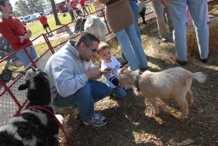 Tim Ellsworth, director of news & media relations, and his son Daniel enjoy feeding a goat at the Arts in the Park event during Homecoming. - Photo by Morris Abernathy