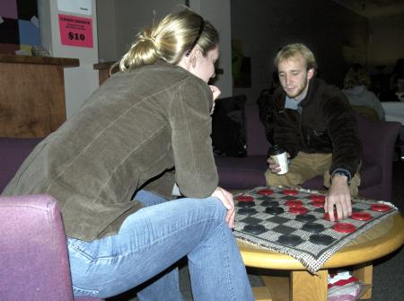 Senior John Kay, history major, plays a game of checkers with Senior Andrea Sarine, nursing major, during the senior class' Ode to Bubba's Bagels party in the student lounge.  - Photo by Matthew Diggs