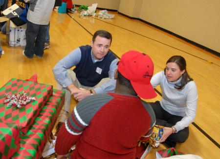 Todd Brady and Julie Bradfield of campus ministries watch as their child opens gifts at the SAC Carl Perkins' Christmas Party. - Photo by Morris Abernathy