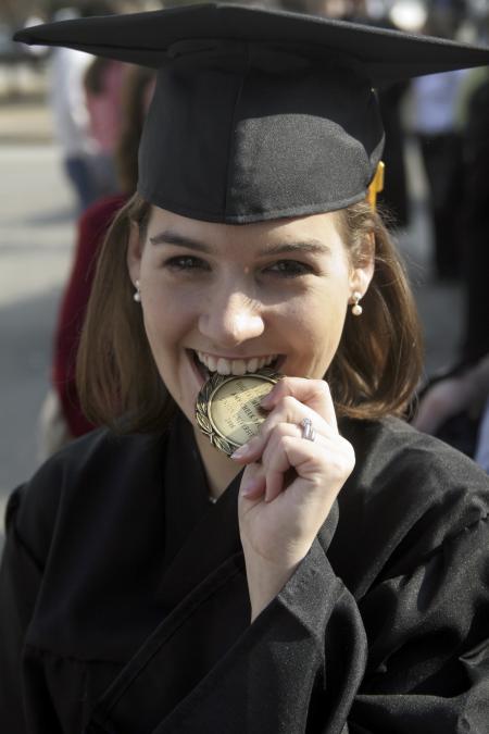 Amy Pfost, digital media studies graduate, celebrates by chewing on her academic excellence medal after fall graduation. - Photo by Kyle Kurlick