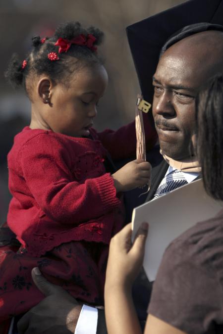 Marlon Heidelberg, MBA graduate, celebrates with his daughter Mackenzie while greeting friends and family after fall graduation. - Photo by Kyle Kurlick