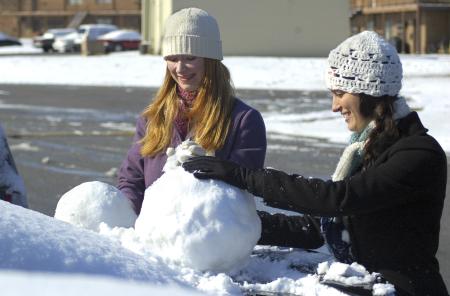 Junior Sarah Nadaskay (right), english major, and Senior Emily Hurst (left), learning foundations major, build snow men on cars. - Photo by Matthew Diggs