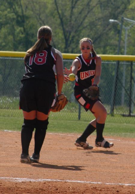 After a bunt, first baseman Brandy Hoffman (18) tosses the ball to Heidi Bybee who is covering first on the play. - Photo by Steven Aldridge
