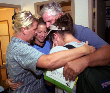 After moving in to her first dorm room, freshman Lindsey Stavish prays with her family before they leave. - Photo by Justin Veneman