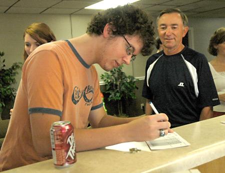 Freshman Blake Emerson, digital media studies major, signs into his room in the Watters commons as his father Steve Emerson looks on.  - Photo by Matthew Diggs