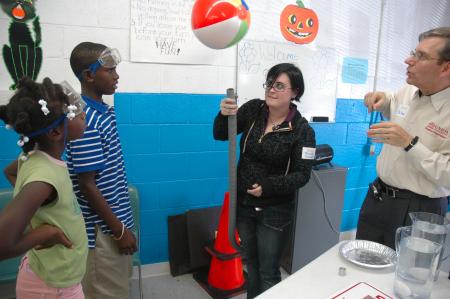 Michelle Thornhill and David Ward, professor of physics, show some children at a Boys and Girls Club some basic physics principles.  - Photo by Neisha Fuson