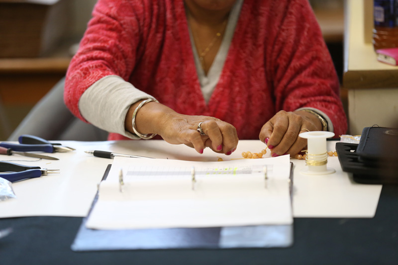 Ran, a Nepali refugee, assembles a necklace for Ekata Designs.