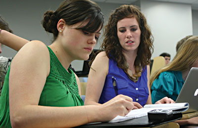 Abby Williams (left) gets help from teammate Kylie McDonald in preparing for the final round in the 2012 International Public Debate Association championship tournament